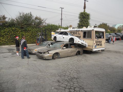 1986 Ford Bronco - A scene of multiple cars stacked on top of each other and a bus, with graffiti and sponsorship text visible.