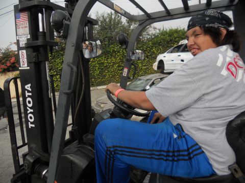 1986 Ford Bronco - A person operates a Toyota forklift, with another vehicle visible in the background.