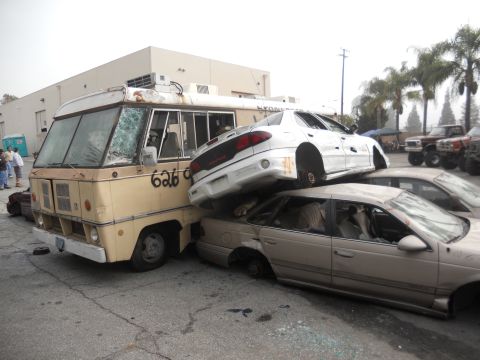 1986 Ford Bronco - A van is crushed by two cars, with the number '626' spray-painted on its side, in a scene that appears to be from a car crush event.
