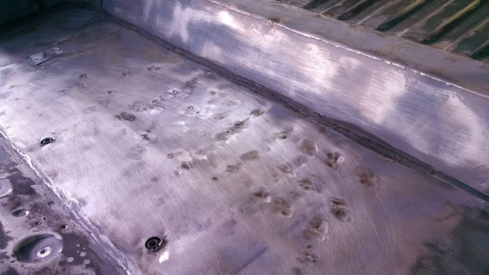 Metal floor with dents and bolts, showing signs of repair