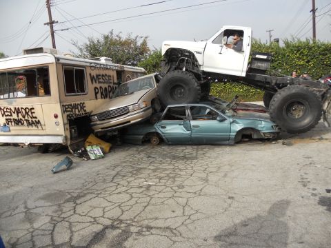 1986 Ford Bronco - A monster truck is shown crushing several vehicles, including a bus, in a junkyard scene.