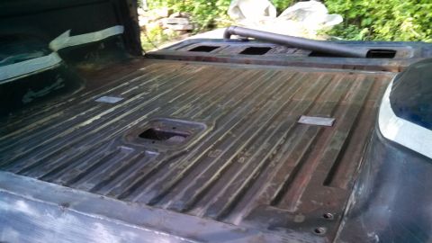 1979 Ford Bronco - The ribbed flooring of a truck bed is visible, with tape on the interior side panel.