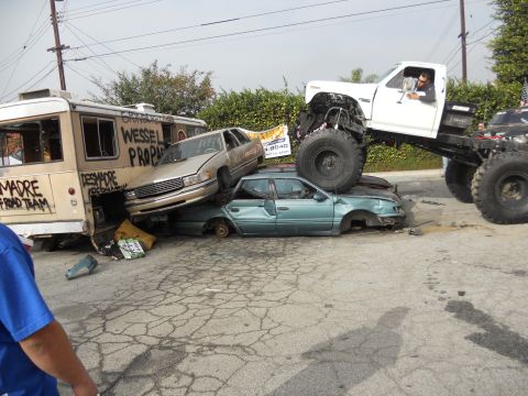 1986 Ford Bronco - A monster truck is shown crushing several cars, with a bus also present in the scene.