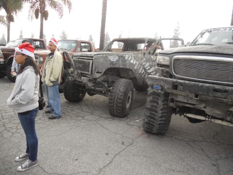1986 Ford Bronco - Modified trucks with people in Santa hats gathered together.