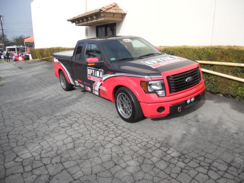 1986 Ford Bronco - This Ford F-150 pickup truck features Optima Batteries branding and a distinctive red and black paint scheme.