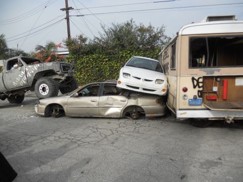 1986 Ford Bronco - A chaotic scene of multiple wrecked vehicles, including a bus and several cars, piled on top of each other.