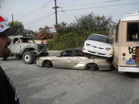 1986 Ford Bronco - Multiple vehicles are wrecked and piled up in a junkyard setting.
