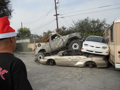 1986 Ford Bronco - A lifted truck is piled on top of two wrecked cars, with a white car and bus also involved in the pile-up.