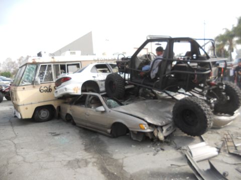 1986 Ford Bronco - A chaotic scene of multiple vehicles crushed and stacked, including a custom buggy.