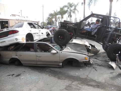 1986 Ford Bronco - A custom off-road buggy is positioned precariously on top of a stack of damaged vehicles.