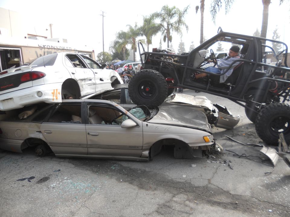 Off-road buggy crushing wrecked cars, one on top of another