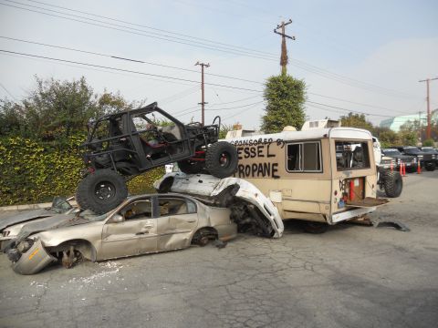 1986 Ford Bronco - A scene of destruction with a buggy perched atop wrecked sedans and a bus.