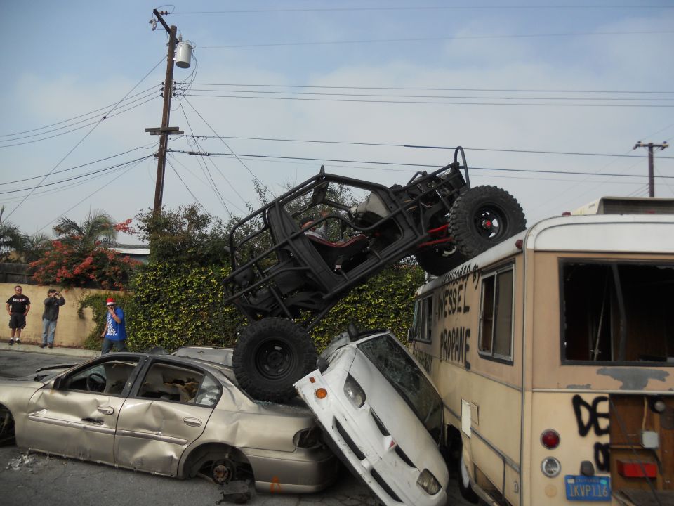 Off-road vehicle atop a bus, crushing cars below