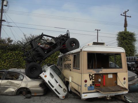 1986 Ford Bronco - A chaotic scene with multiple wrecked vehicles piled up, including an off-road buggy perched atop a bus.