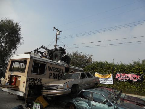 1986 Ford Bronco - A collection of vehicles, including a bus and several cars, are piled up in an outdoor lot.