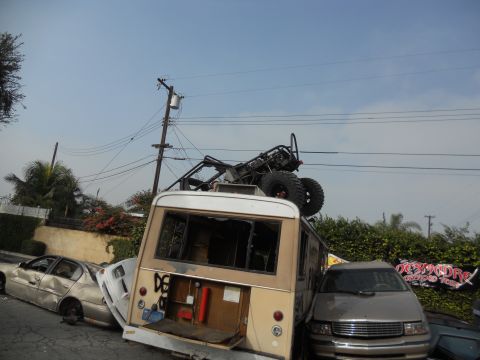 1986 Ford Bronco - Multiple vehicles are piled up, including an off-road buggy on top of a van.