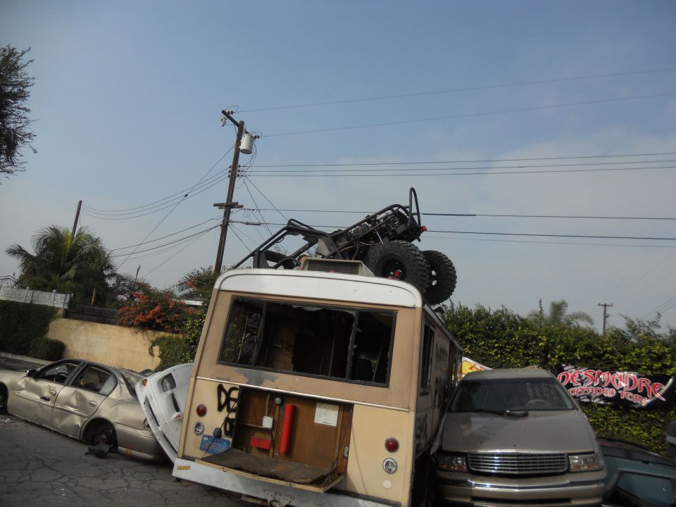Off-road buggy loaded onto a van, with a sedan and minivan also visible