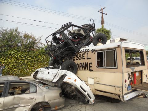 1986 Ford Bronco - A chaotic scene with a buggy perched atop crushed vehicles and a bus.