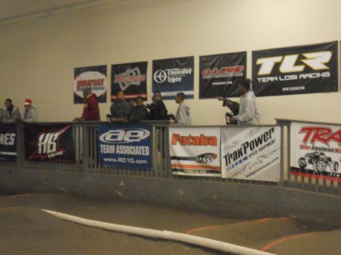 1986 Ford Bronco - Spectators observe an indoor RC car race track, with various sponsor banners displayed along the wall.