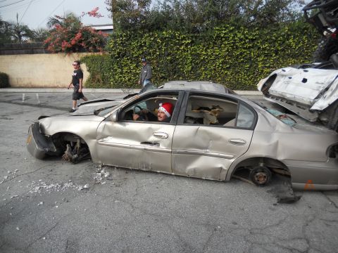 1986 Ford Bronco - This heavily damaged sedan has no wheels and a person in a Santa hat is in the driver's seat.