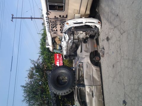 1986 Ford Bronco - A severely damaged car is wedged against the side of a bus, indicating a significant collision.