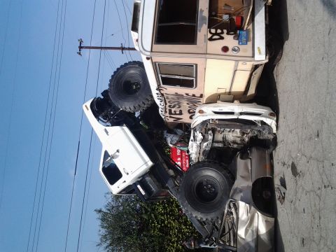 1986 Ford Bronco - A chaotic scene of multiple crushed vehicles, including a truck and RV, piled atop each other on a street.