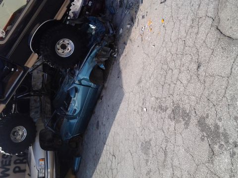 1986 Ford Bronco - A teal SUV, possibly a 1986 Ford Bronco, is heavily damaged and appears to be part of a car crush event.