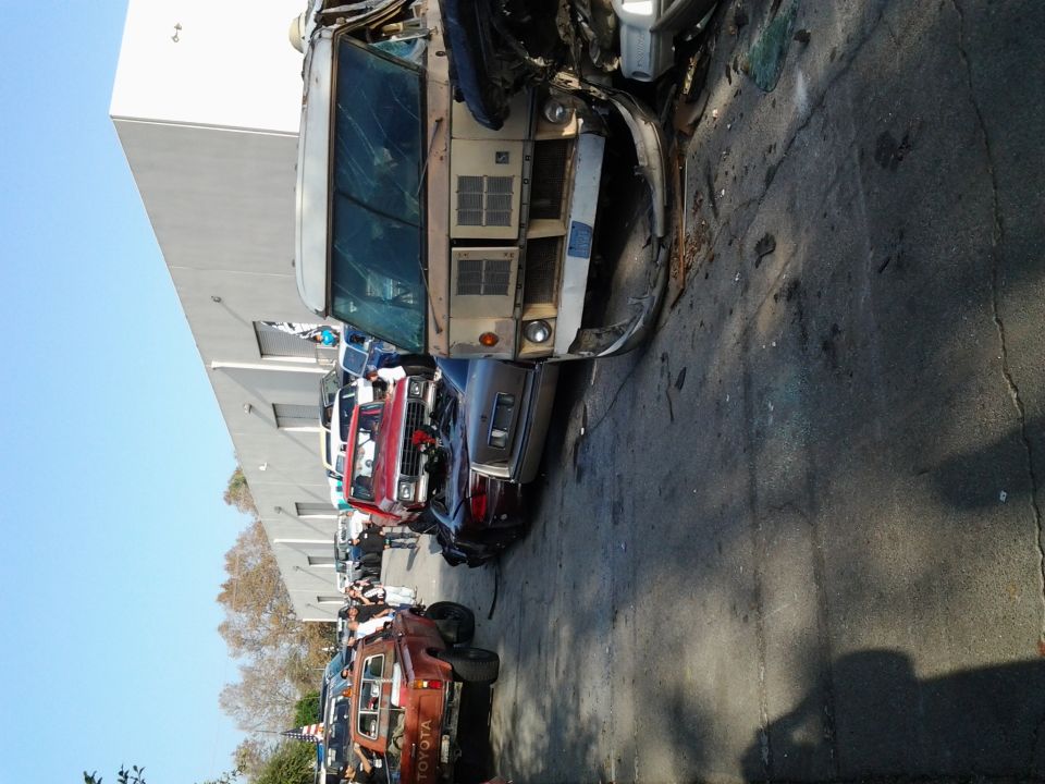 Line of wrecked vehicles, including a tan van and a red pickup truck