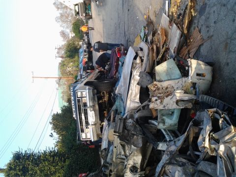 1986 Ford Bronco - A pile of mangled car parts surrounds a lifted Ford truck at a junkyard.