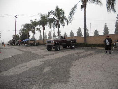 1986 Ford Bronco - A lifted pickup truck is parked outdoors with palm trees in the background.