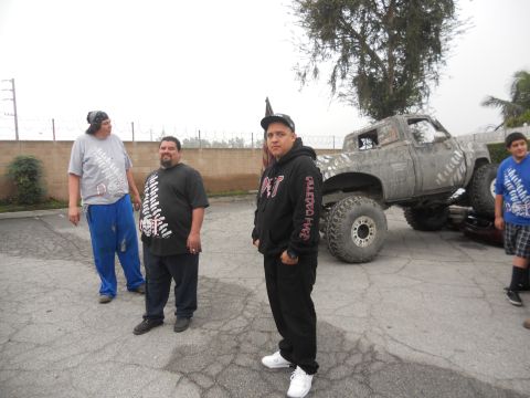 1986 Ford Bronco - A heavily modified pickup truck with oversized tires is the focus of this scene, with several people standing nearby.