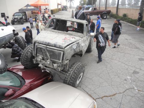 1986 Ford Bronco - A heavily modified 1973 GMC pickup truck, covered in mud, sits parked on top of other vehicles.