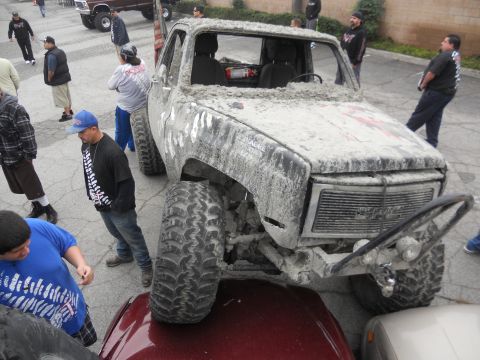 1986 Ford Bronco - Mud-covered pickup truck with large tires and a detached steering wheel is the focus of attention.
