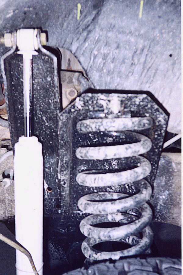 Close-up of a vehicle's front coil spring and shock absorber assembly