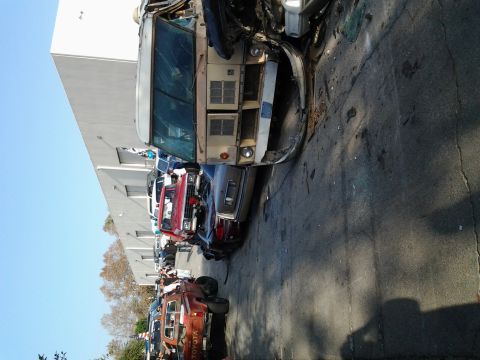 1986 Ford Bronco - Multiple damaged vehicles are parked in a line outside a building.