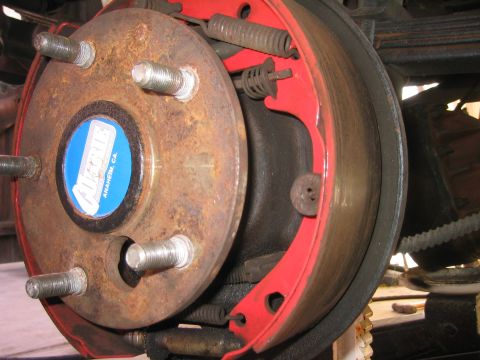 1969 Ford Bronco - Close-up of a vehicle's rear brake assembly, showing a rusty drum and red brake shoes.