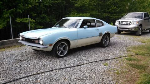 1973 Ford Maverick - A light blue and cream 1973 Ford Maverick is parked on a gravel driveway next to a silver pickup truck.