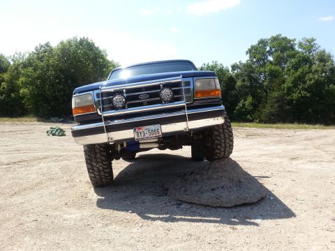 1995 Ford Bronco - 1995 Ford Bronco front view, navigating an obstacle on a dirt trail.