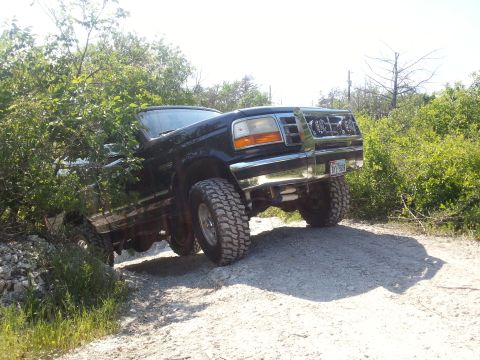 1995 Ford Bronco - This 1995 Ford Bronco is shown navigating a rough dirt trail with its suspension lifted and large off-road tires.
