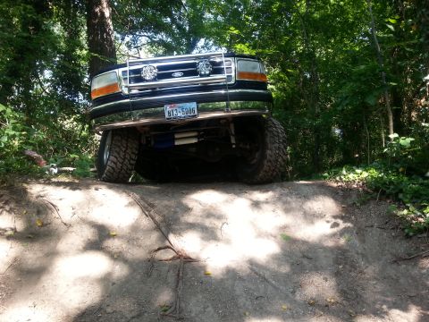 1995 Ford Bronco - 1995 Ford Bronco navigating an off-road trail with its front wheels on an incline.