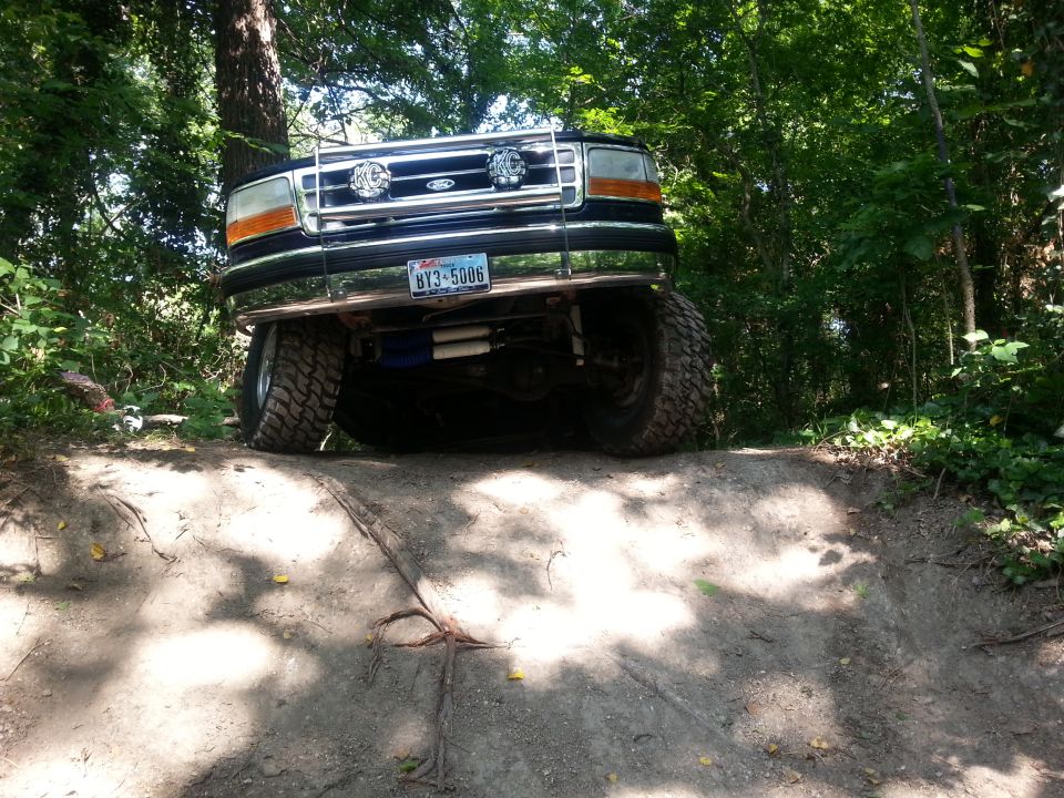 1995 Ford Bronco front view on dirt trail with trees in background. License plate BY3-5006