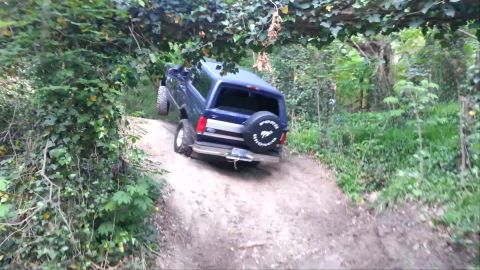 1995 Ford Bronco - A blue 1995 Ford Bronco navigates a challenging off-road hill climb.
