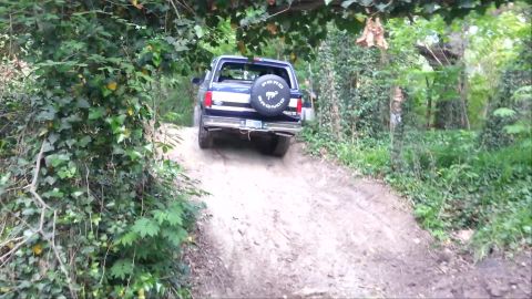 1995 Ford Bronco - A Ford Bronco navigates a steep, dirt path through a wooded area.