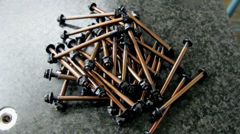 1996 Ford Bronco - A pile of bolts with nuts is shown on a speckled surface.