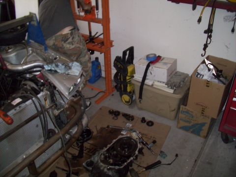 1995 Ford Probe - A cluttered garage scene displays disassembled engine parts, tools, and various workshop equipment.