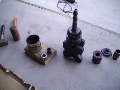 1995 Ford Probe - Various gears, bearings, and tools are arranged on a concrete floor, suggesting a mechanical repair or assembly.