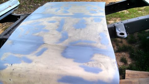 1979 Ford Bronco - A vehicle hood is shown with primer and body filler applied, indicating preparation for repair or painting.