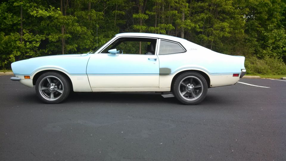 Two-door coupe with light blue and white two-tone paint, aftermarket wheels, and a gray patch on the rear quarter panel