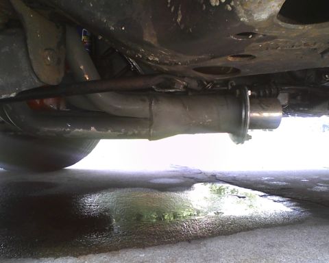 1975 Chevrolet Chevelle - A view of the vehicle's exhaust system, with puddles reflecting the sky beneath.