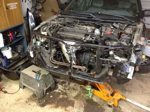 1988 Ford Bronco - The front end of a car is disassembled, revealing the engine and surrounding components in a workshop.